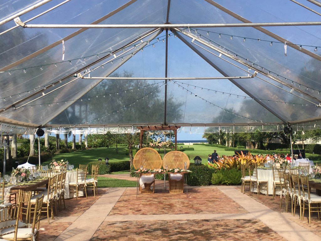 South Florida wedding reception under a clear tent with string lights and ocean view