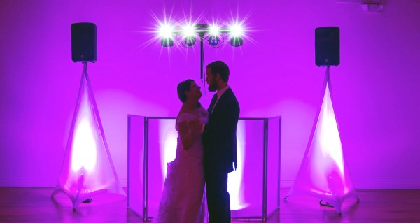 Couple posing in front of an uplit RMP DJ booth