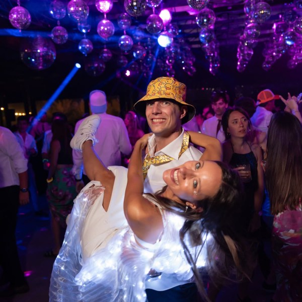 Guests dancing under colorful party lights
