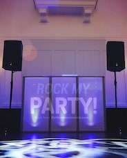 Rock My Party DJ setup with uplit speaker towers and dance floor lighting