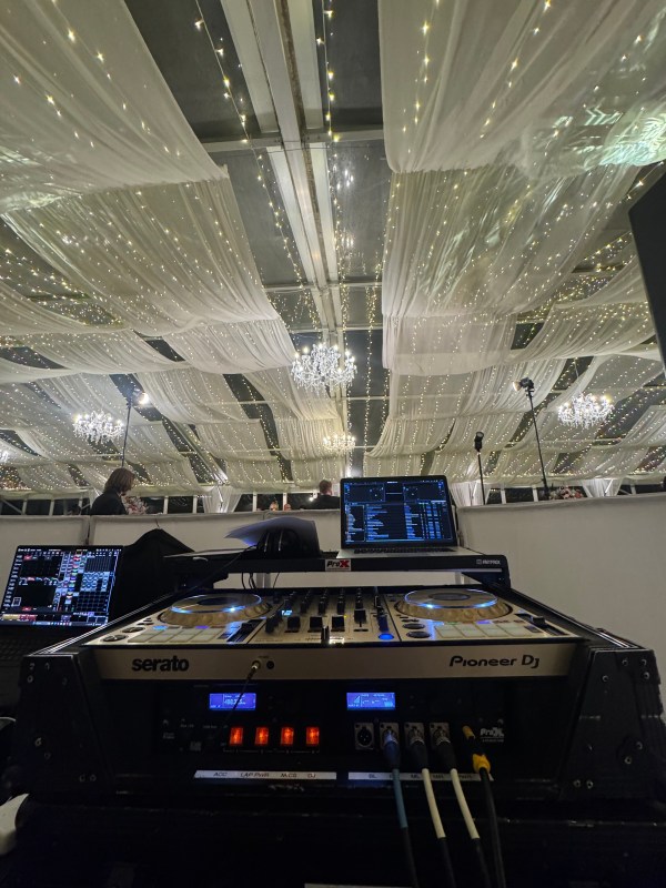 DJ controller and laptop beneath a draped ceiling