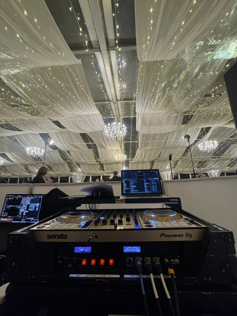 DJ controller and laptop beneath a draped ballroom ceiling